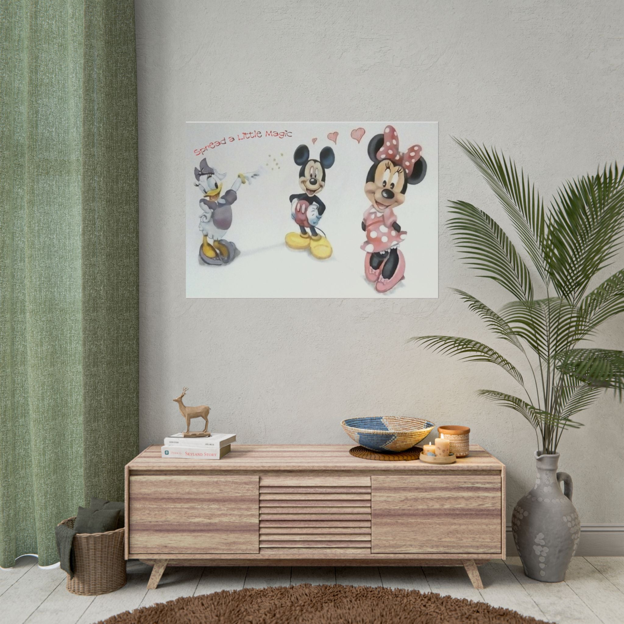 A framed wall art print featuring Mickey Mouse and Minnie Mouse hanging above a wooden console in a styled room with a green curtain, plant, and decorative objects.